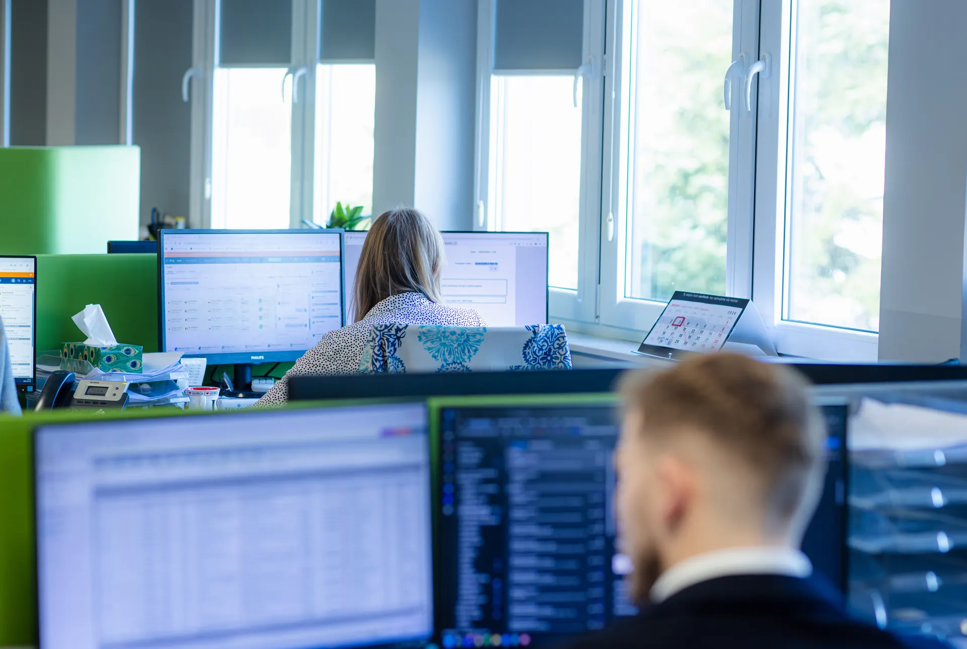 Zespół pracujący przy monitorach w biurze Regesta